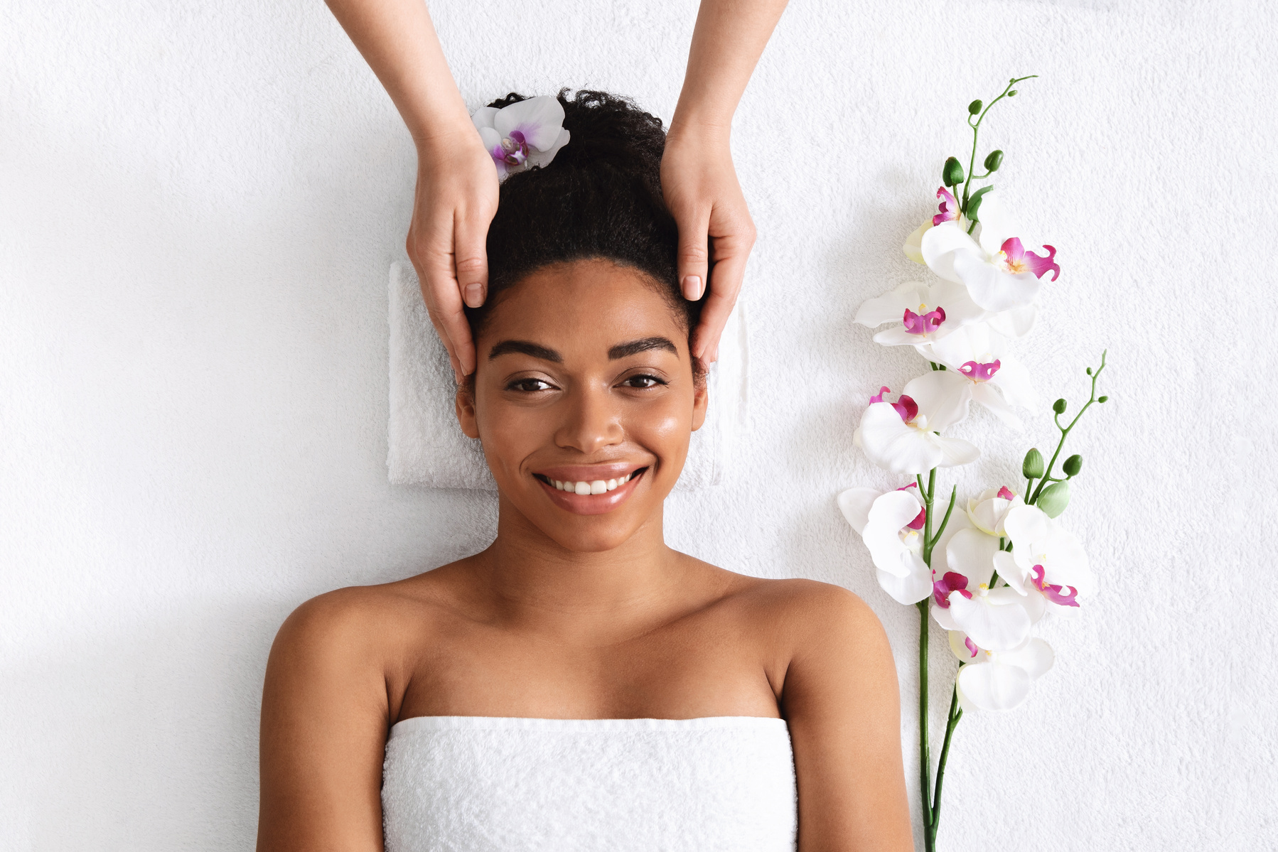 Smiling black girl getting head massage at spa